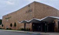 A brick building with a distinctive angled awning under a cloudy sky.