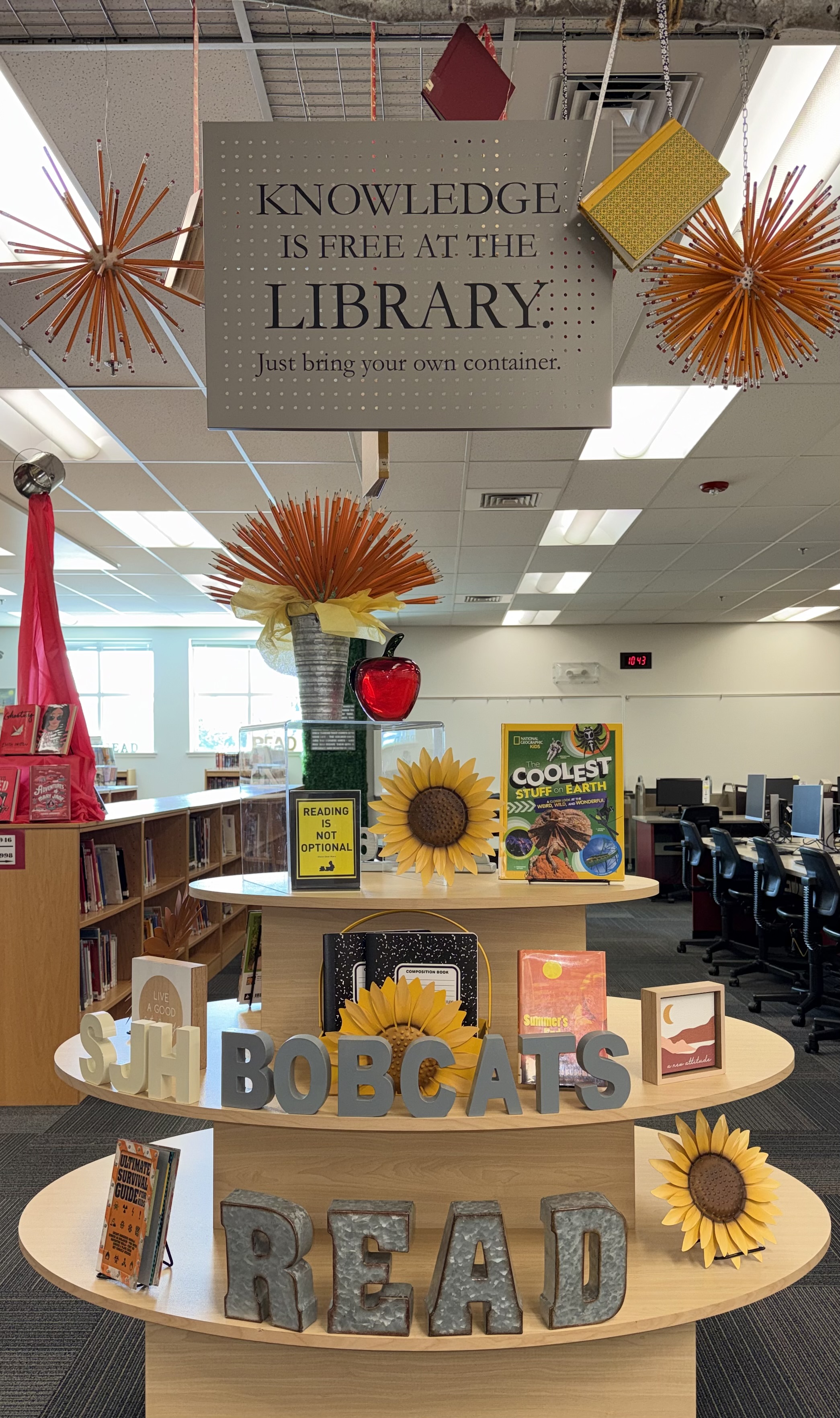 A multi-tiered display in a library features books, sunflowers, and the words "BOBCATS READ."
