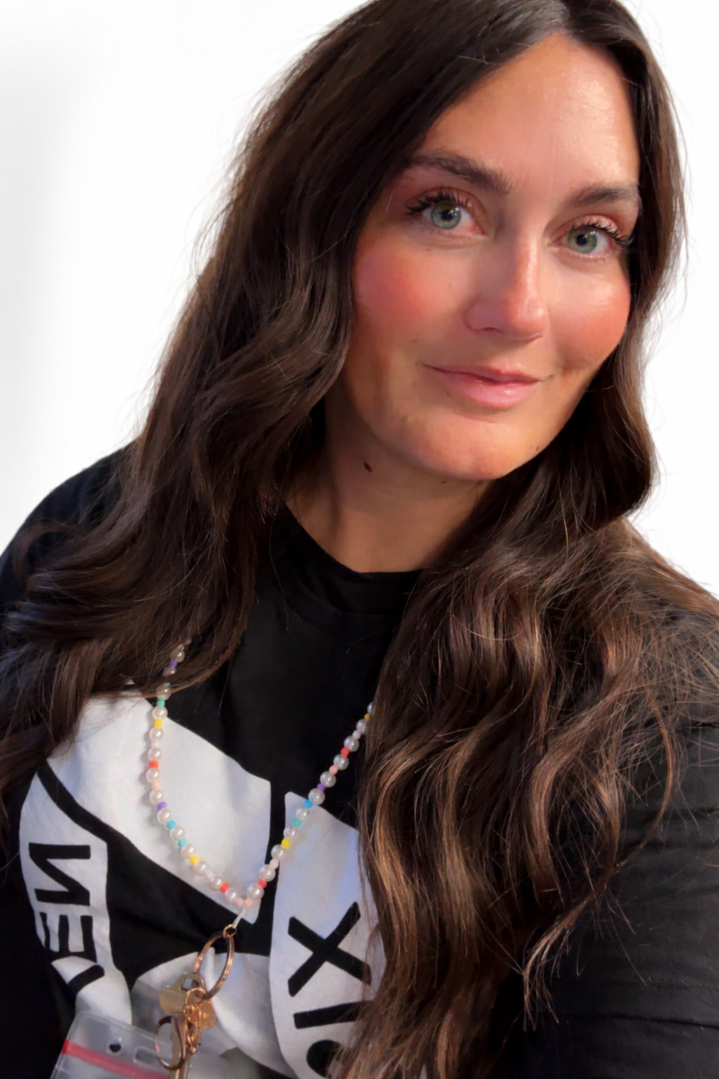A woman with long, wavy brown hair smiles at the camera.