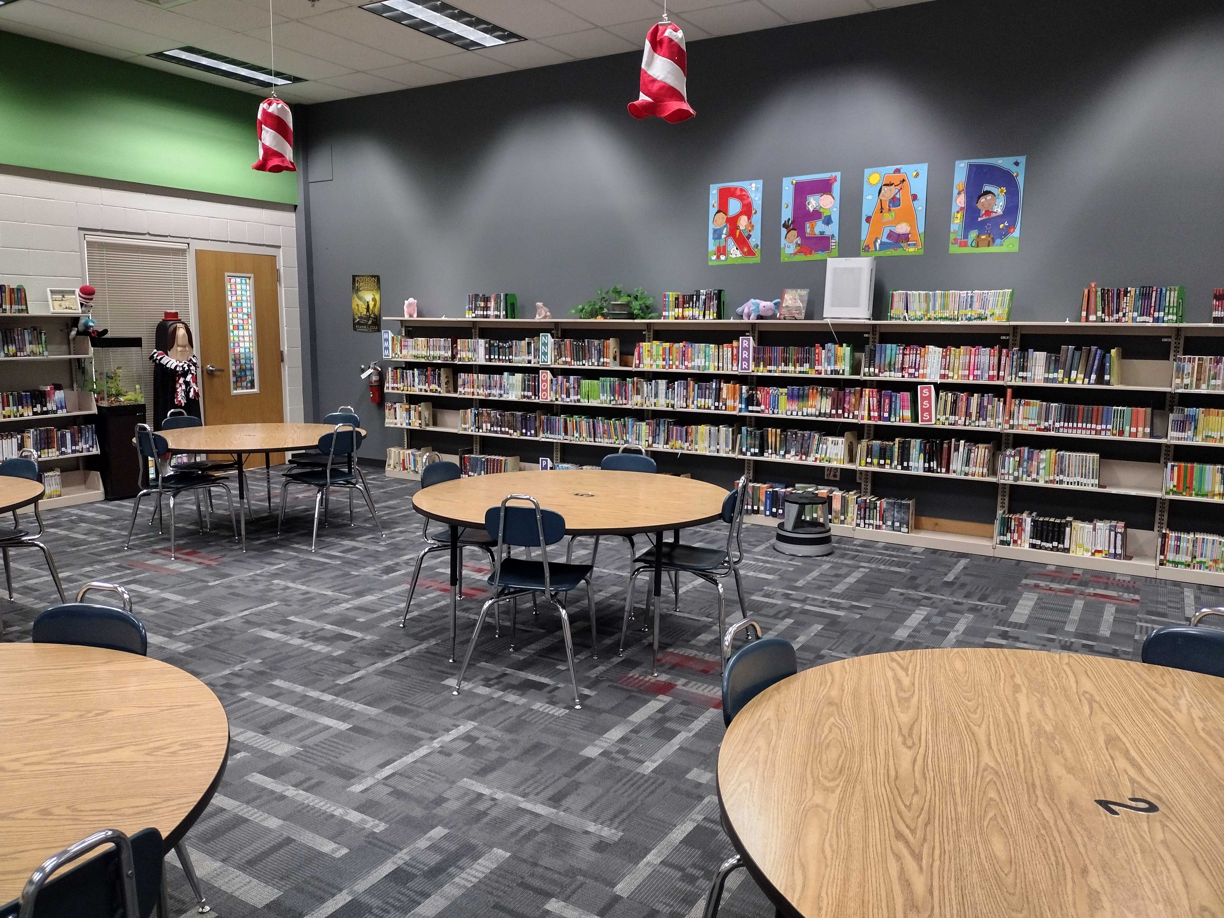 A library interior with bookshelves, round tables, and the word 'READ' displayed.