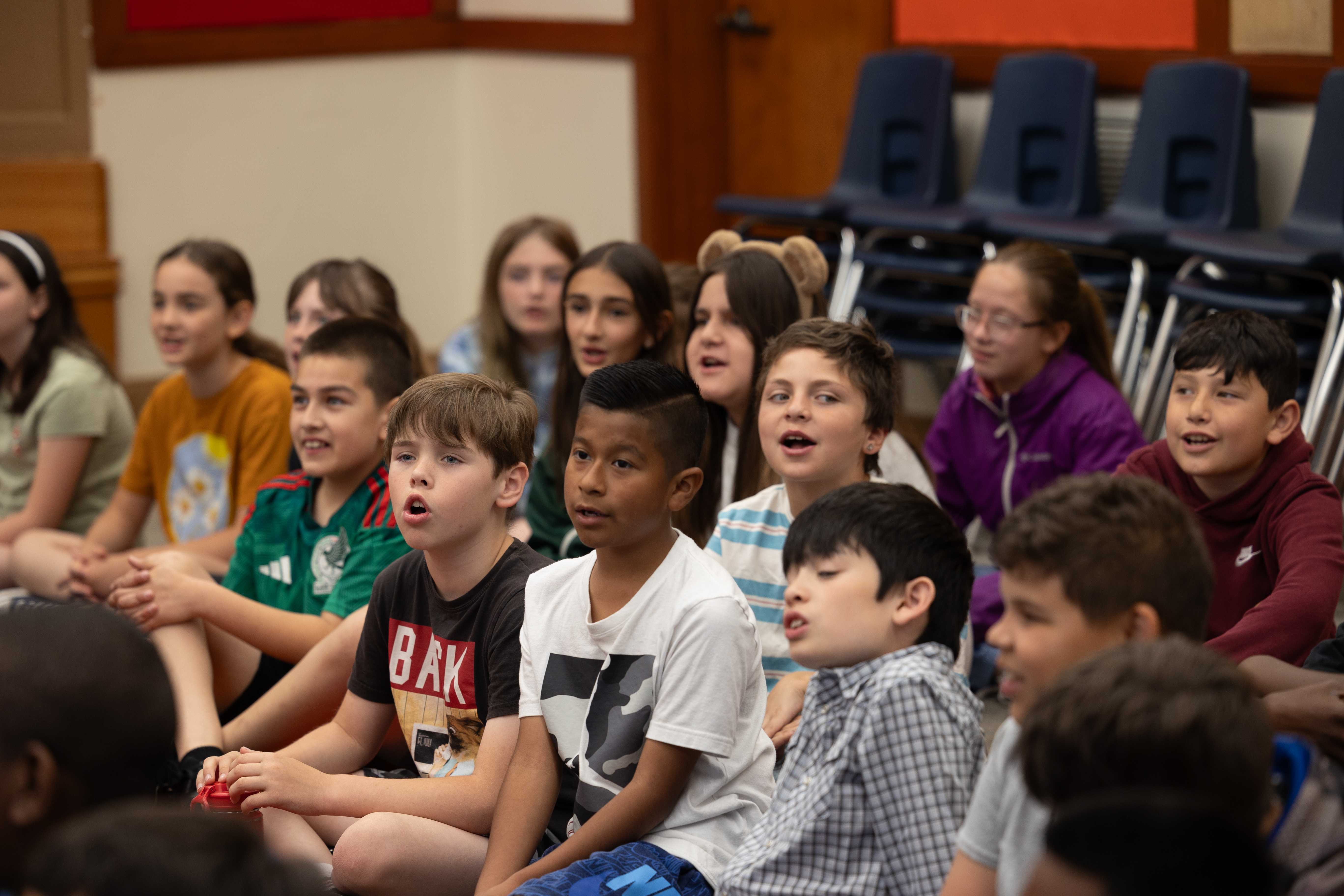 children sitting listening to a teacher