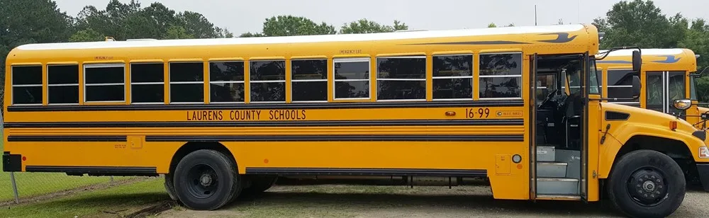 A bright yellow school bus parked outdoors on a cloudy day.