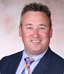 A man with short, styled hair smiles at the camera.