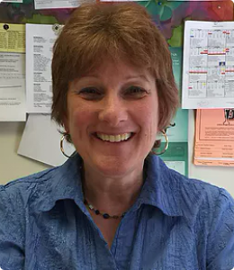 A woman with short brown hair smiles warmly at the camera.