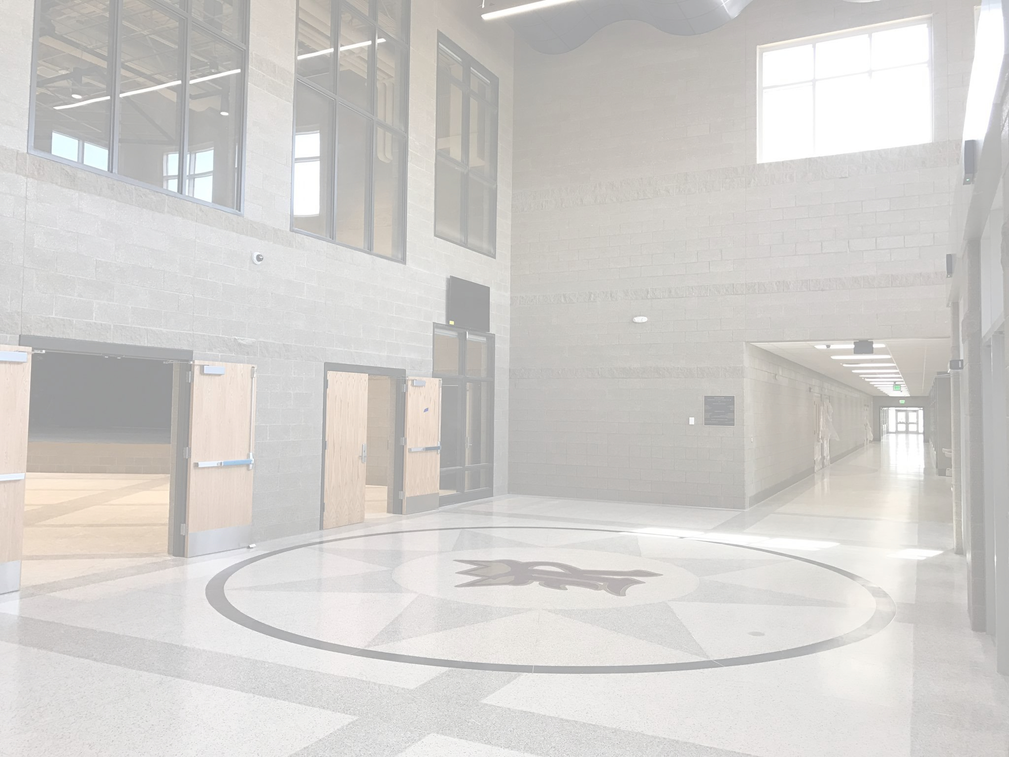 A bright, spacious interior hallway with large windows and a patterned floor.