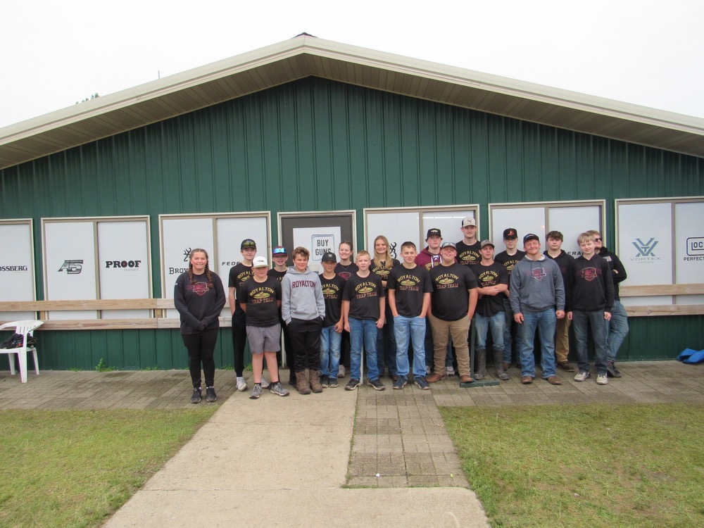 A group of people stand in front of a green building, posing for a photo.