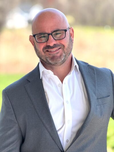 Mike Crocco smiles at the camera outdoors.