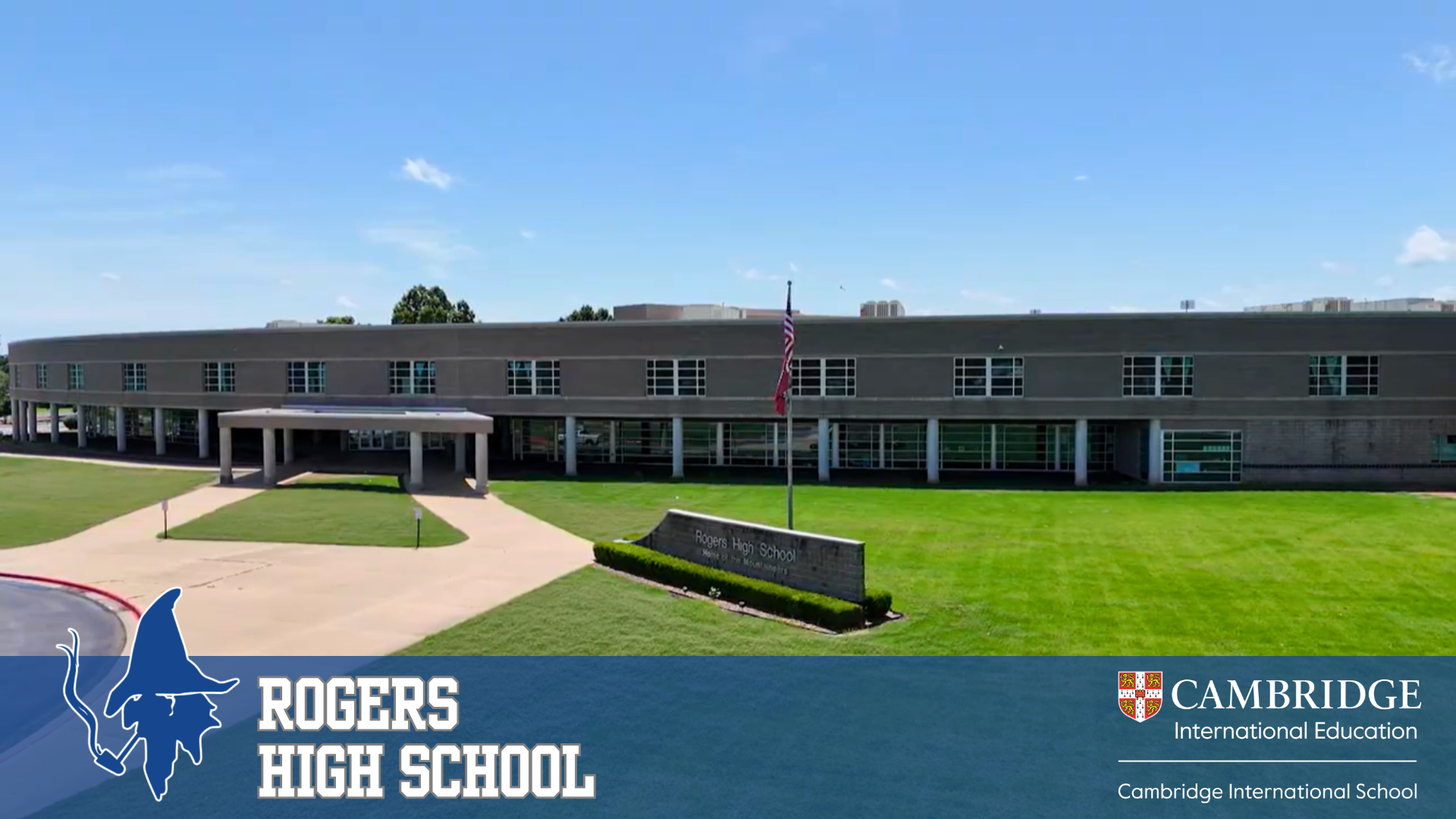 Exterior view of Rogers High School with a large grassy lawn and a flagpole.
