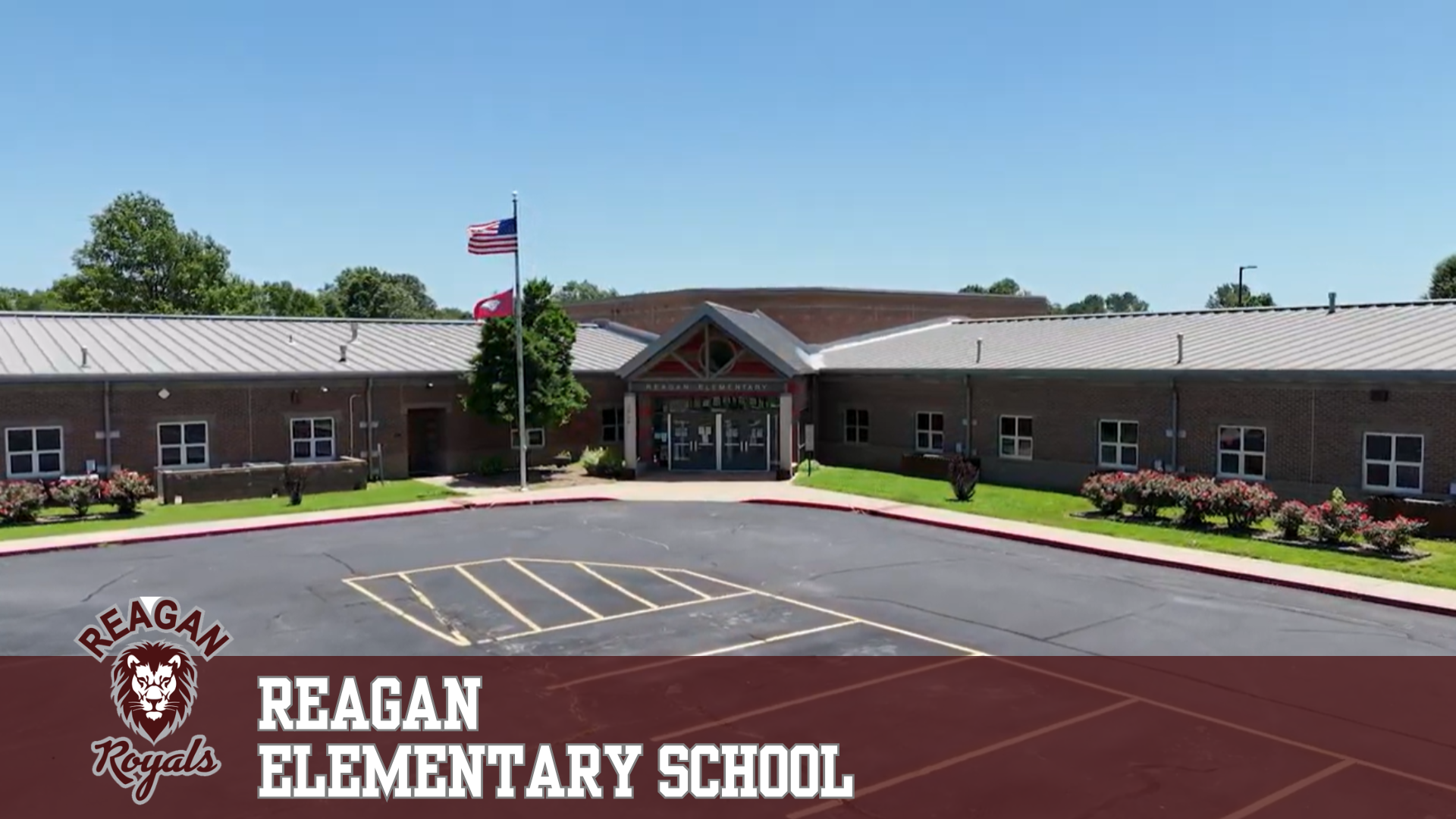 The exterior of Reagan Elementary School on a clear day, with American and school flags flying.
