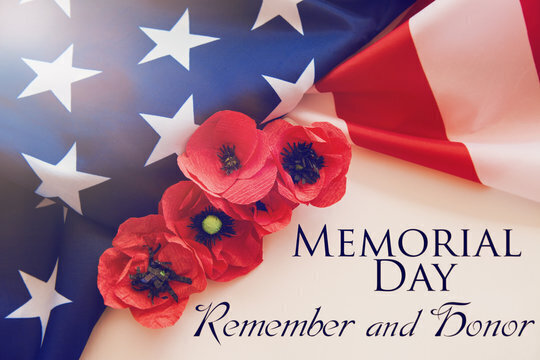 Red poppies rest on a US flag with the text 'MEMORIAL DAY Remember and Honor'.