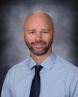 Person wearing a blue shirt and black tie