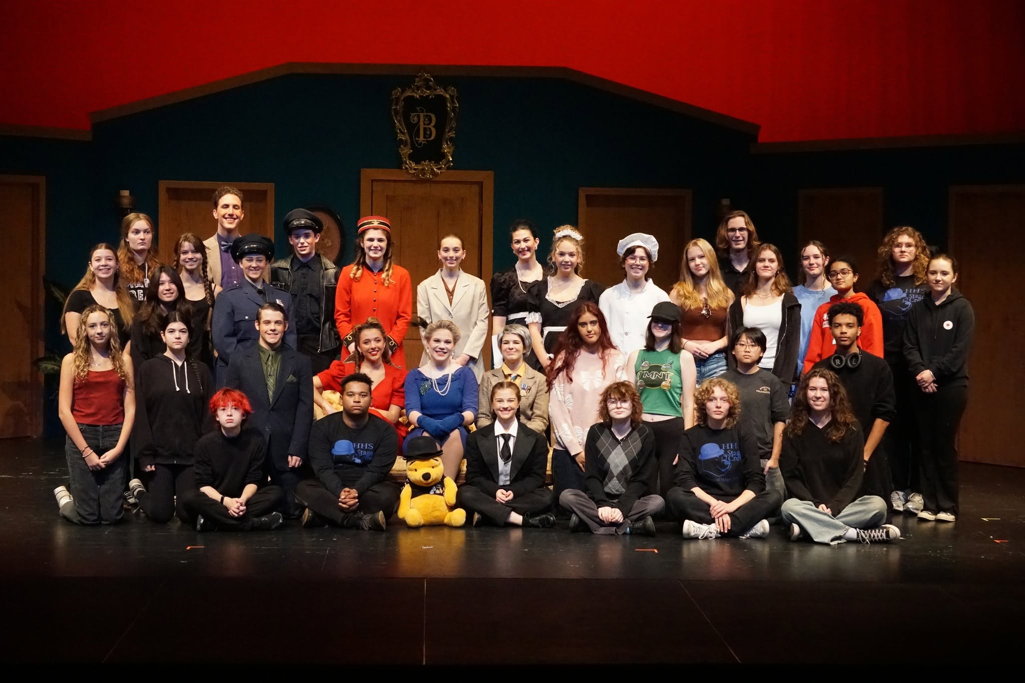 A large group of people in costumes pose for a photo on a stage.