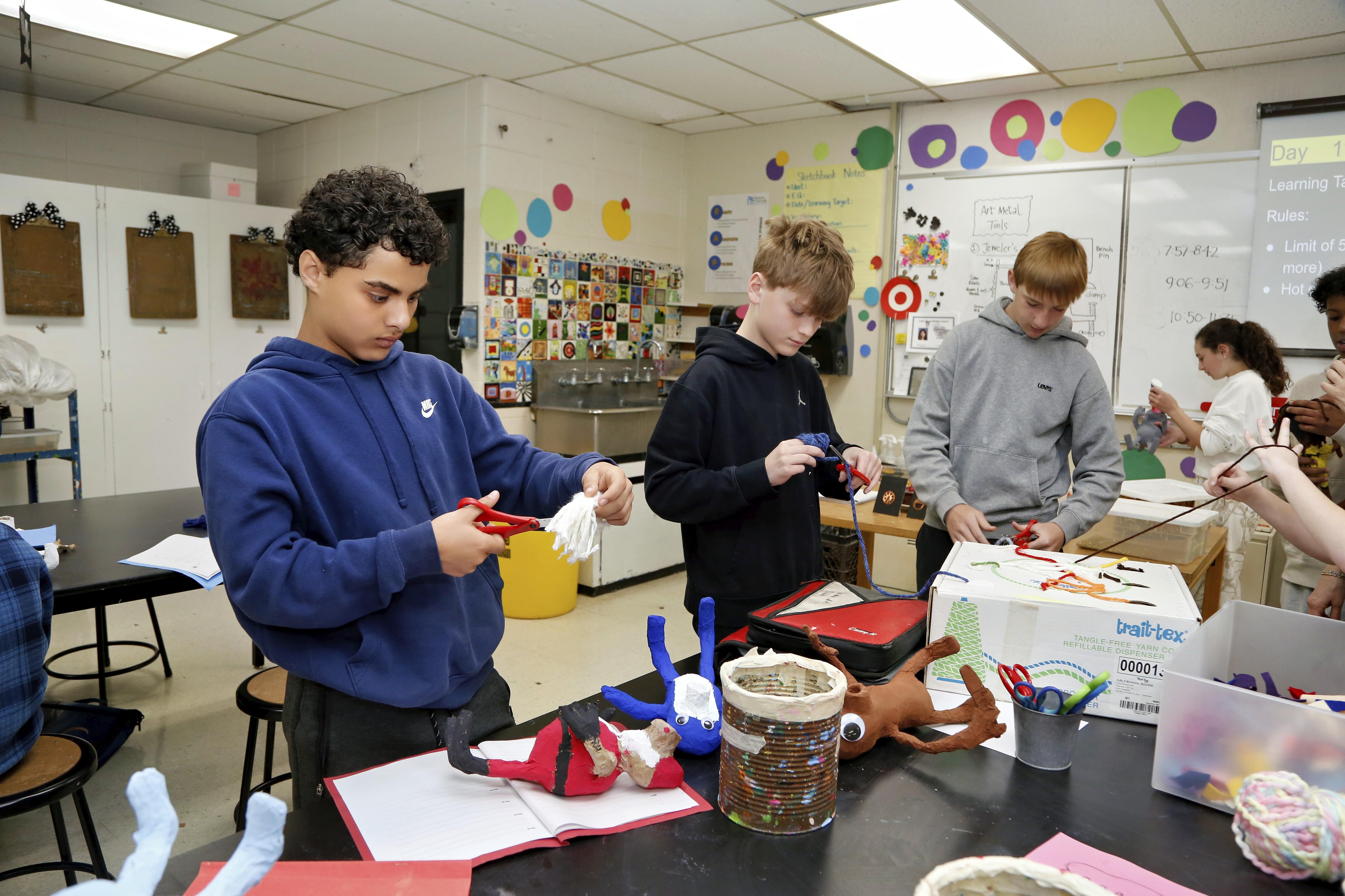 Students engaged in a creative art project, cutting and assembling materials.