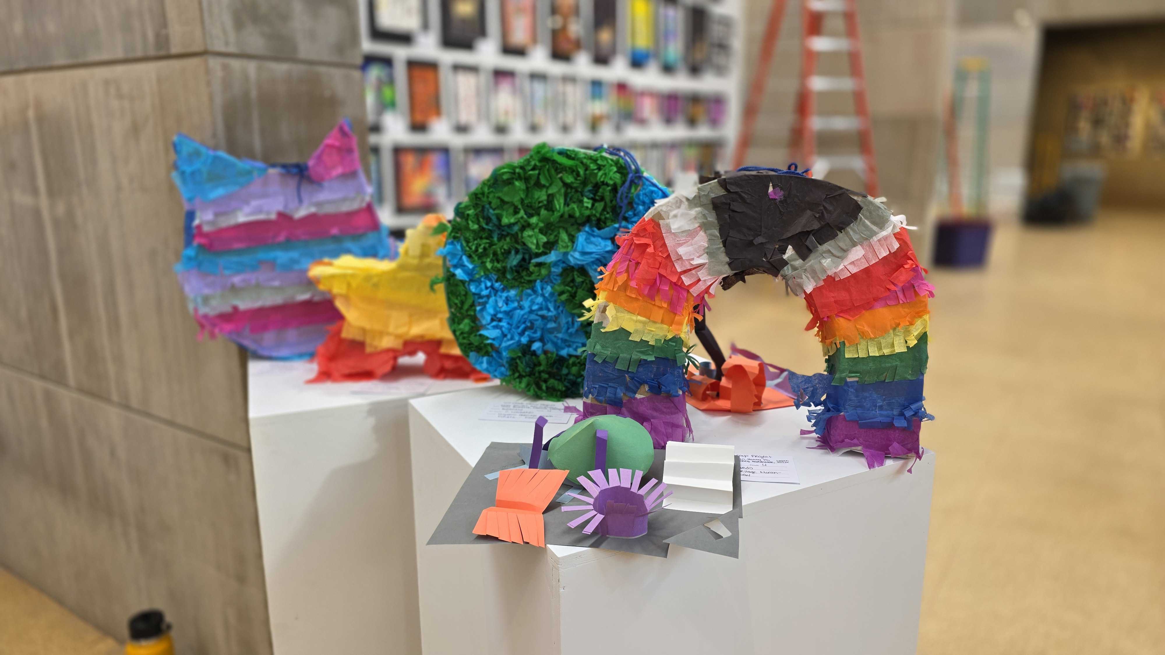 A colorful collection of handmade piundefinedatas, including a globe and a star, displayed on a white pedestal.