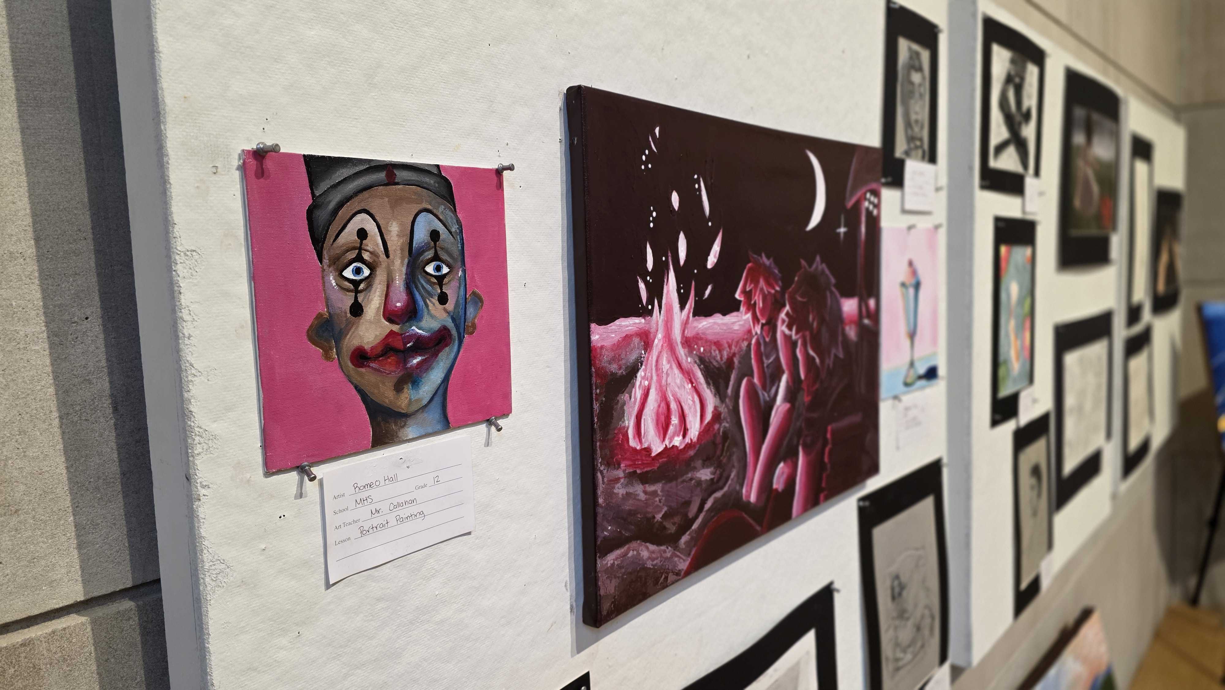 A wall displays a collection of diverse artworks, including a vibrant pink portrait and a dark, surreal landscape.