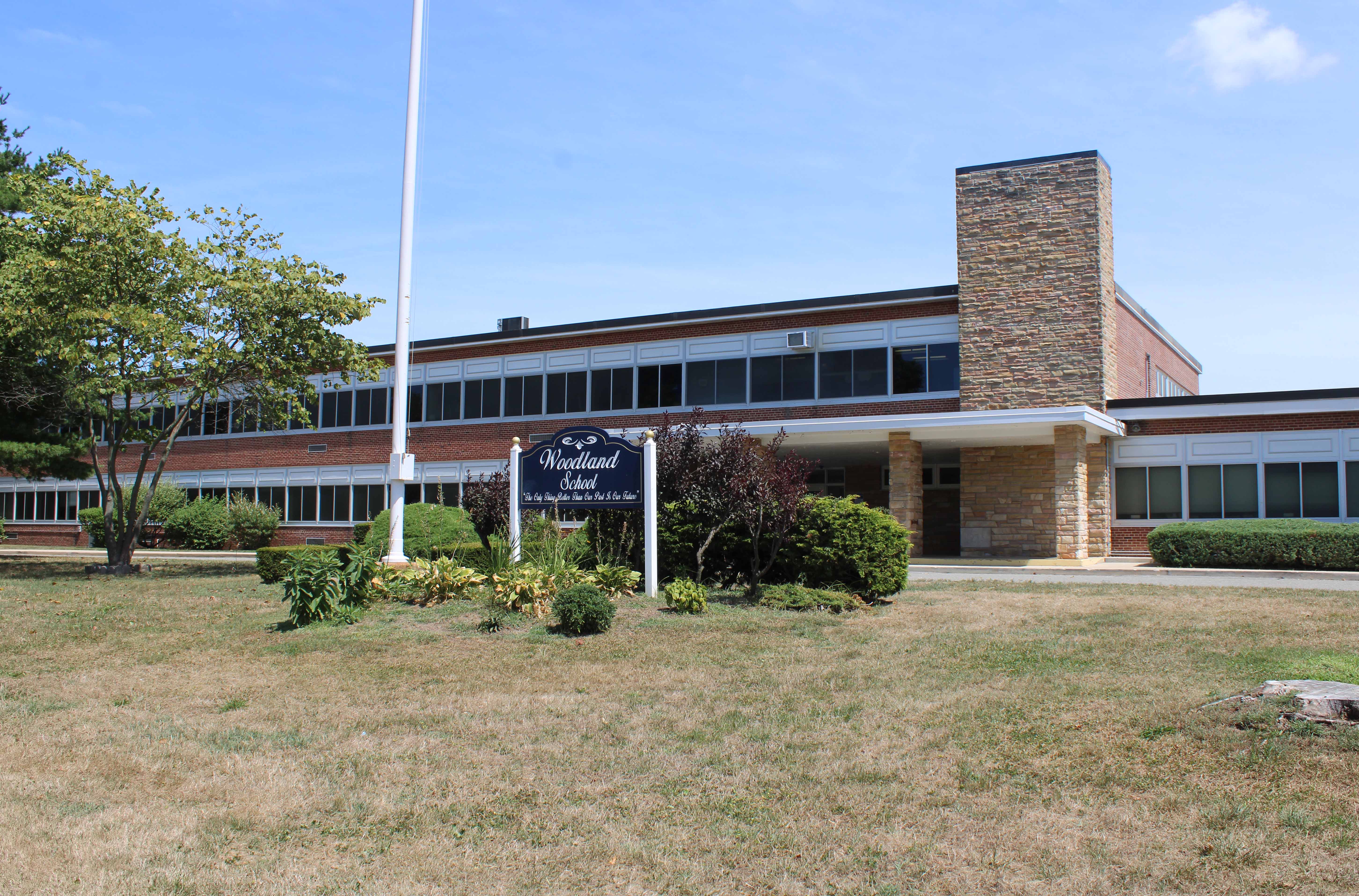 A brick and glass school building with a flagpole in front.