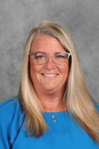 A woman with blonde hair and glasses smiles at the camera.