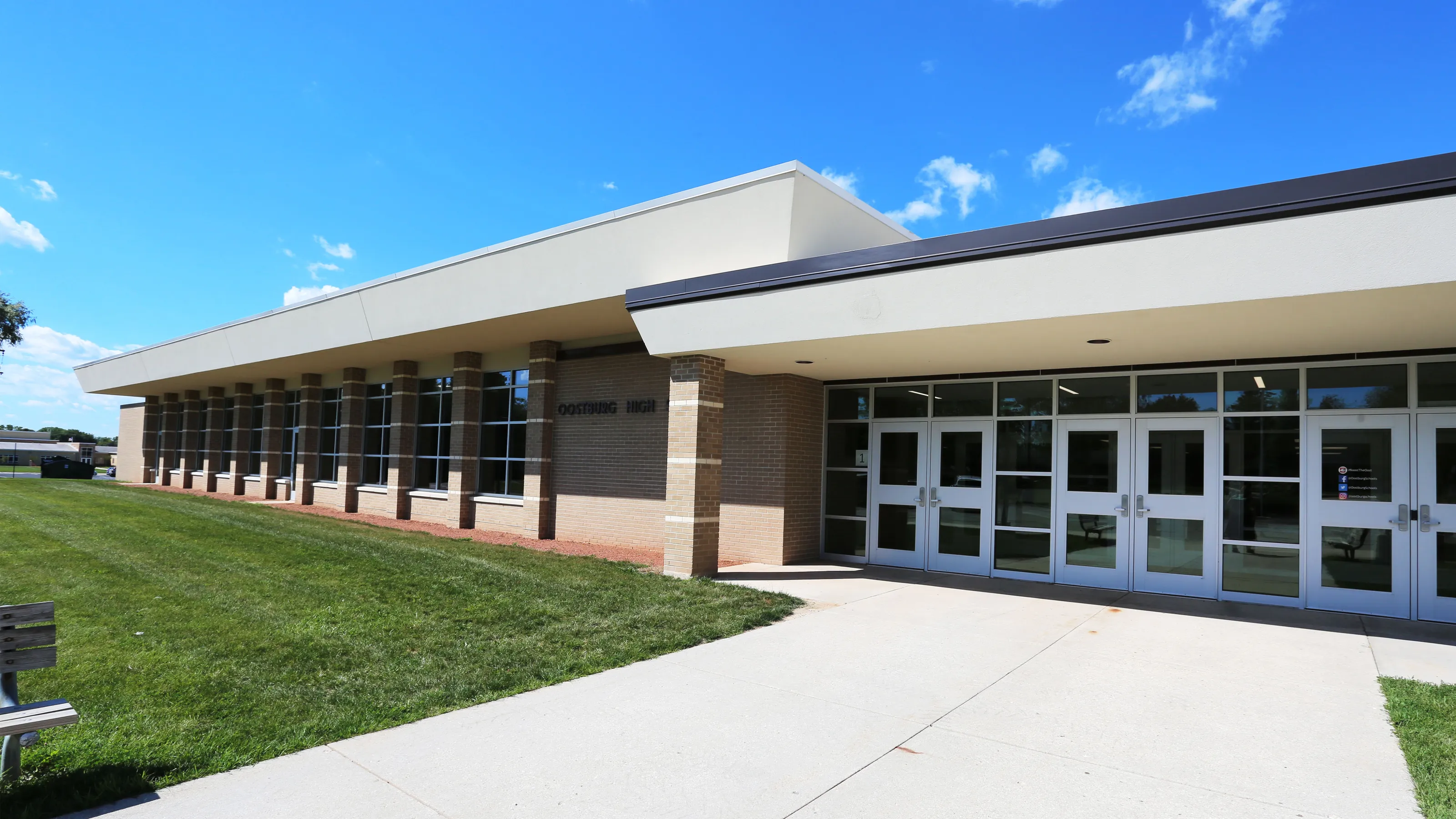 Exterior view of a modern building with large glass windows and a paved walkway.