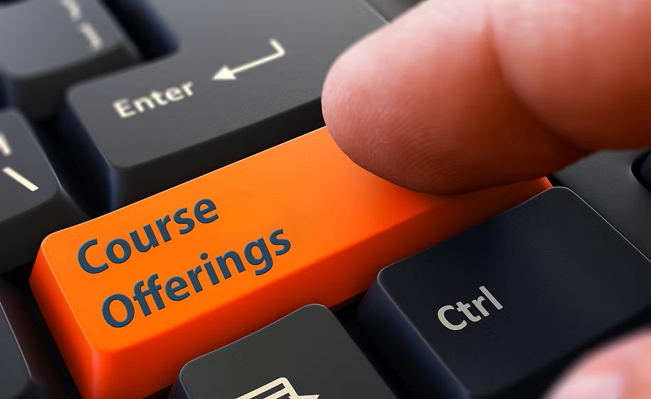 A finger presses the orange 'Course Offerings' key on a computer keyboard.