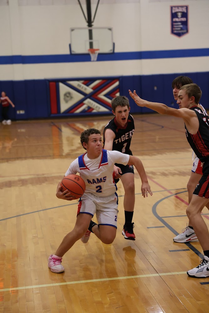 A young basketball player in a white jersey dribbles the ball down the court during a game.