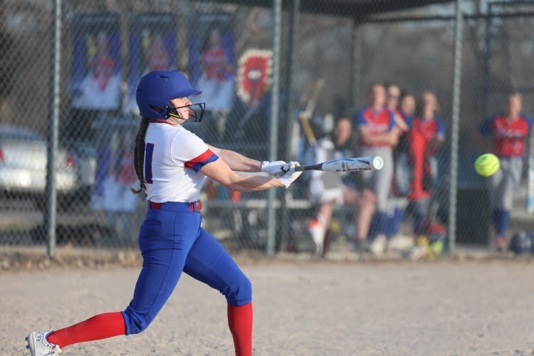A young softball player swings a bat at a pitch during a game.