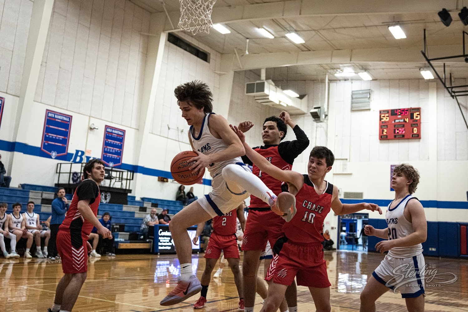 A basketball player in mid-air jumps to shoot the ball during a game.
