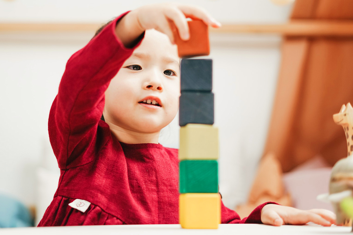 A young child is stacking blocks.