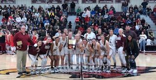 Girls basketball team holding a trophy on the basketball court