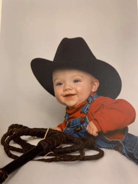 Baby photo of Torqe B. in overalls and a cowboy hat