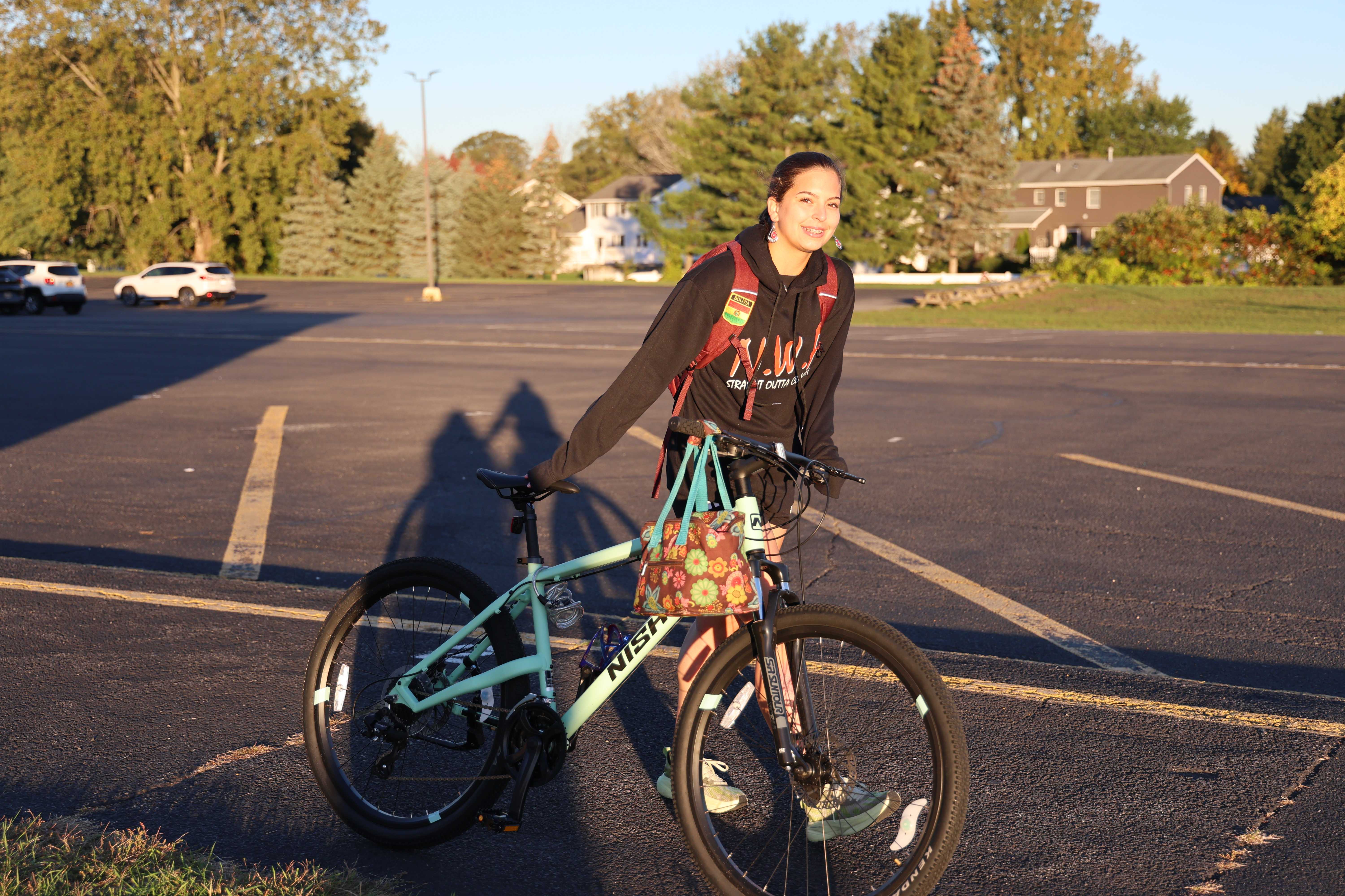 A person smiles while standing next to a bicycle loaded with gear.