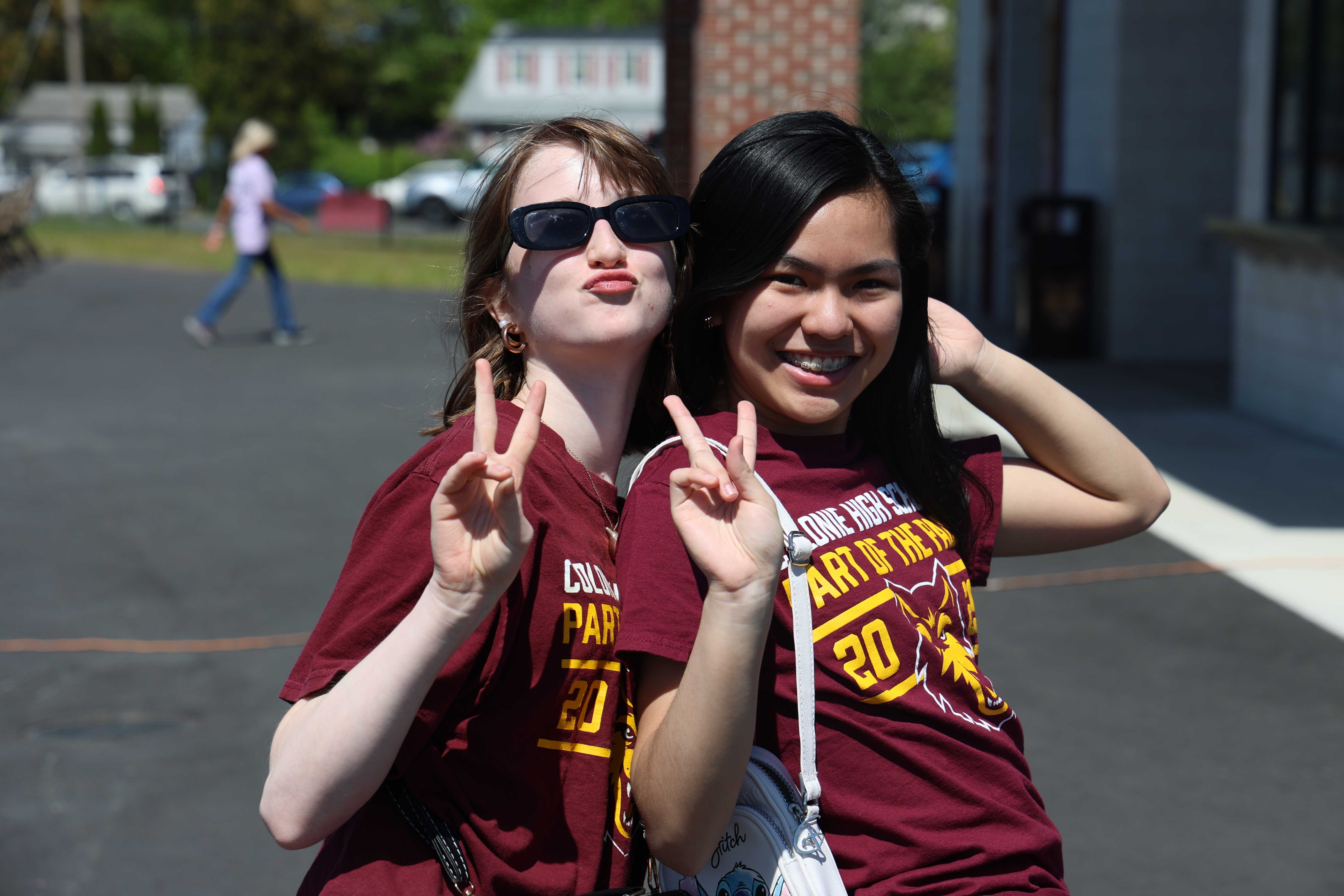 Two young women pose for a photo, making peace signs and smiling.