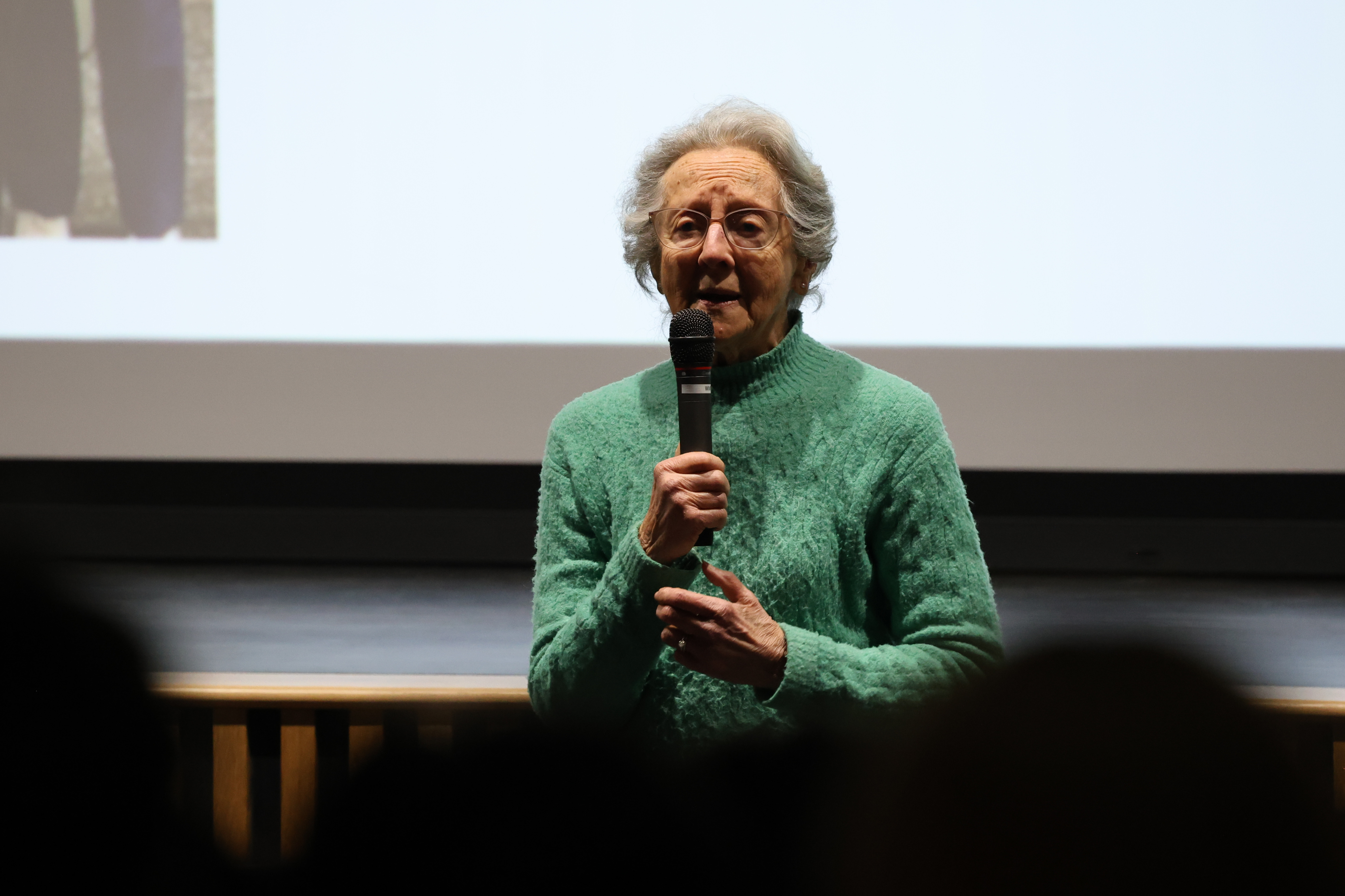 A woman speaks into a microphone on a stage.