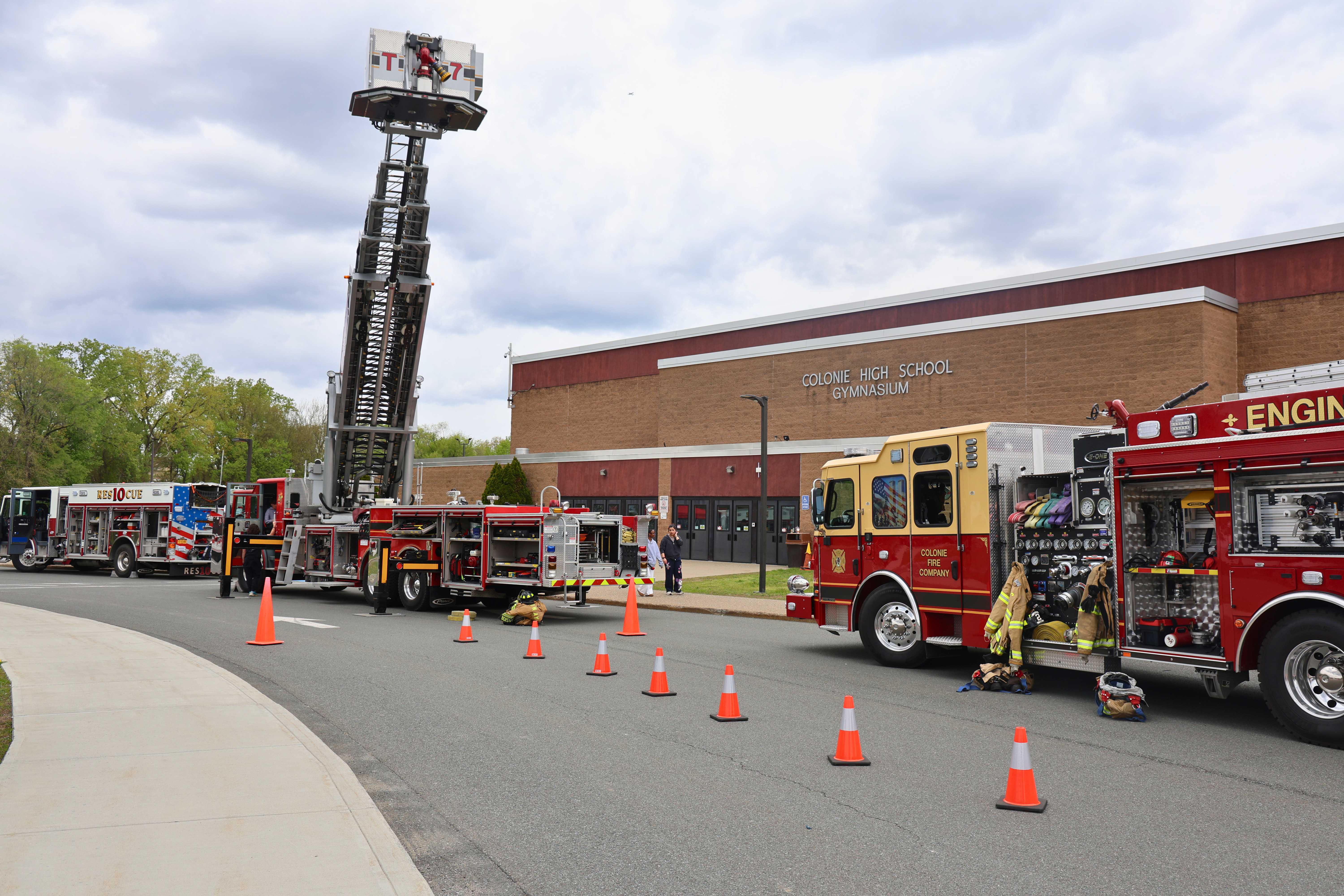 Fire trucks are parked near a building, with an extended ladder.
