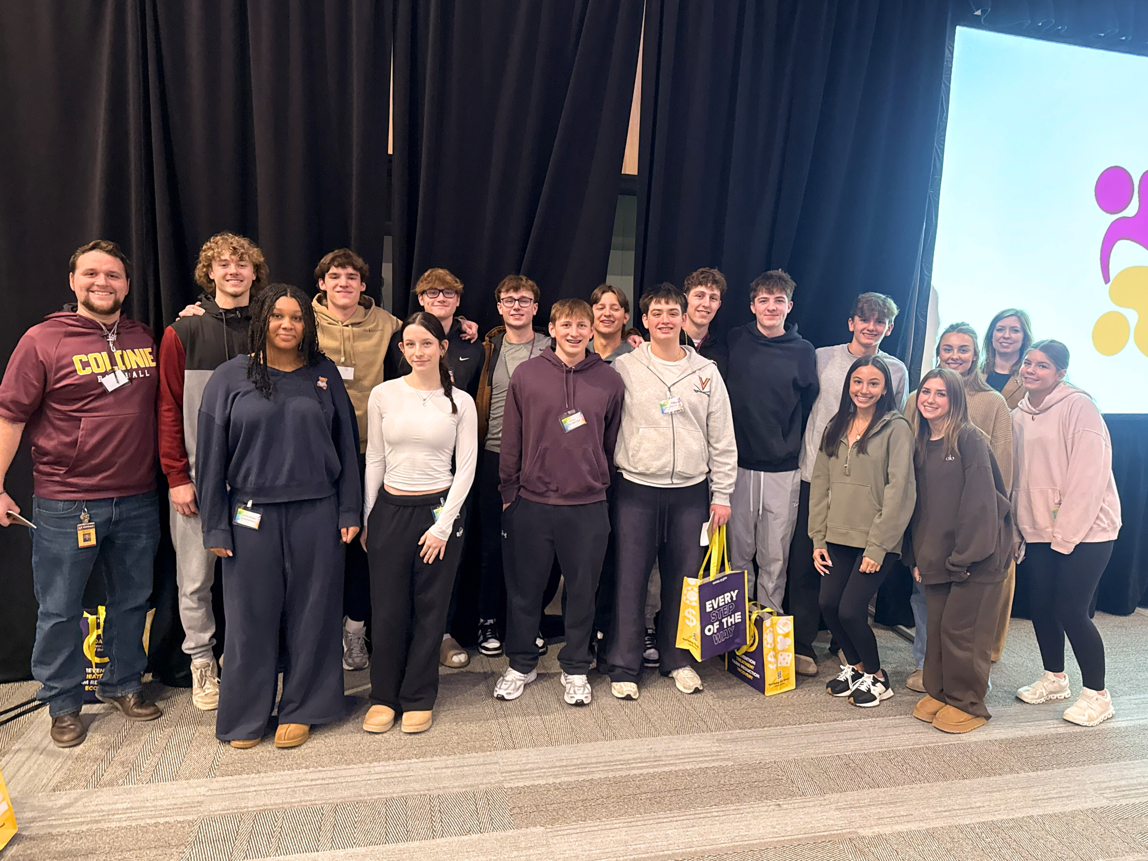 A group of high school students pose for a photo in front of a dark backdrop.