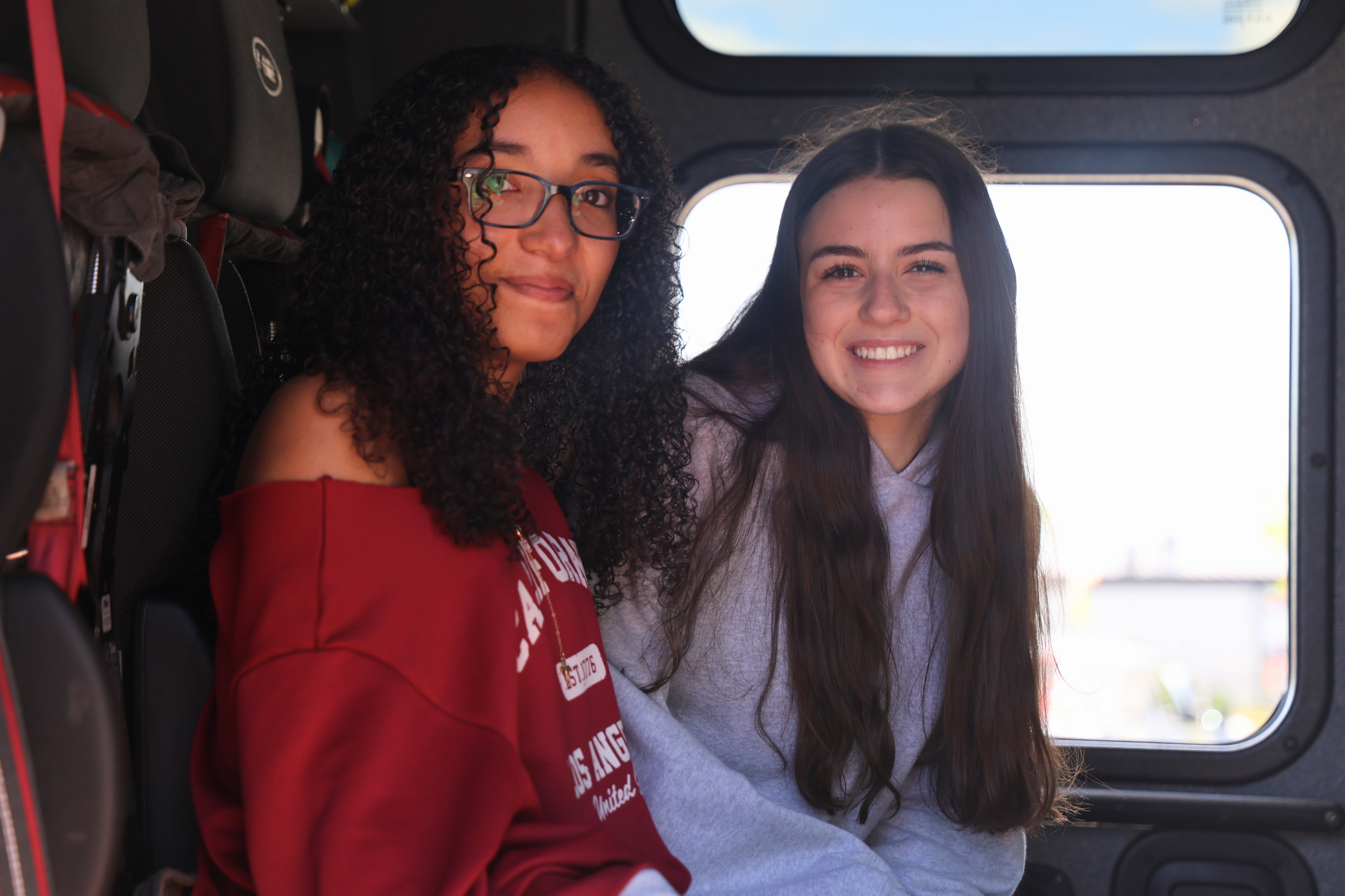 Two young women smile, posing for a photo inside a firetruck.