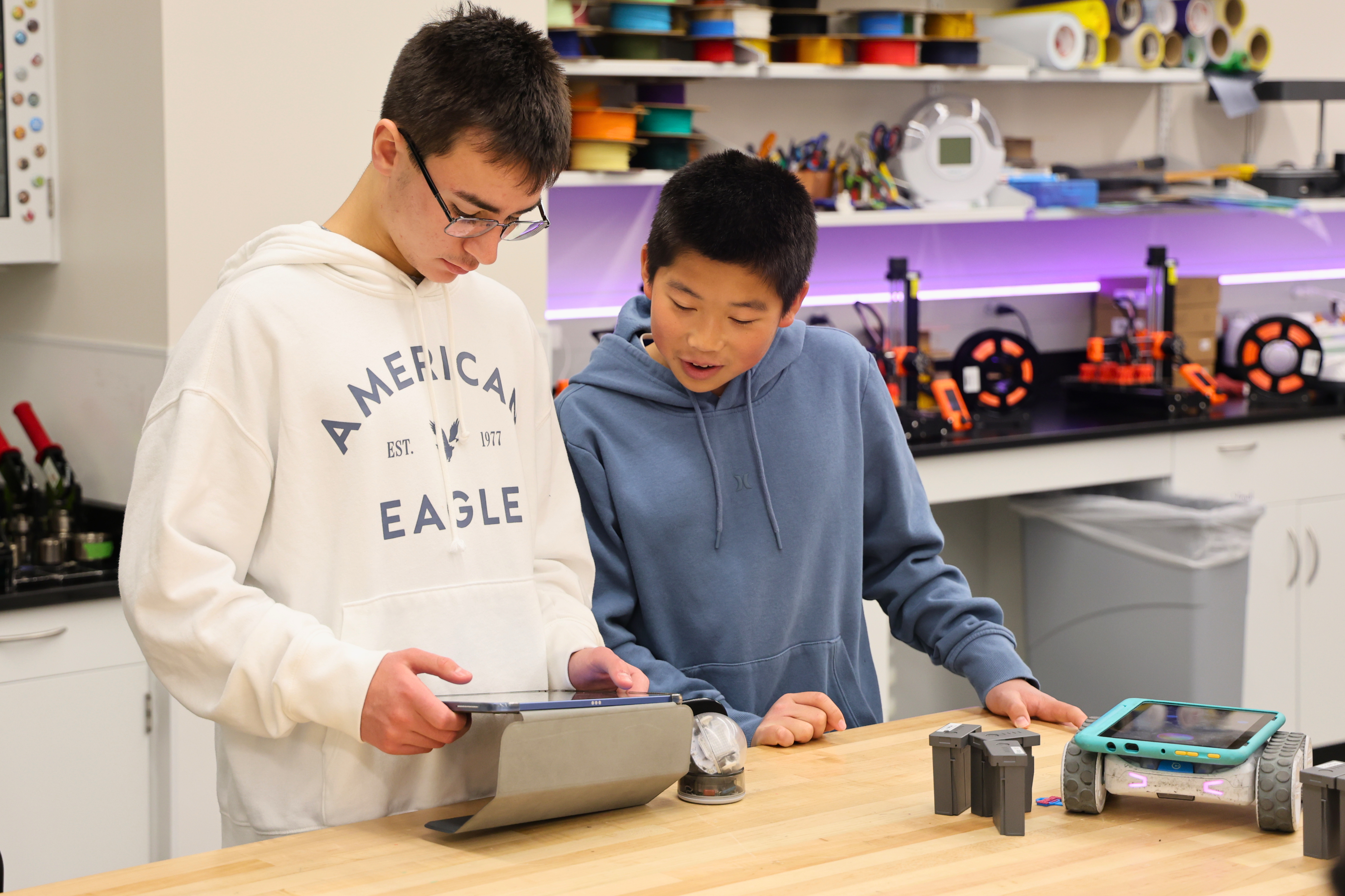 Two young people examine a tablet in a workshop setting.