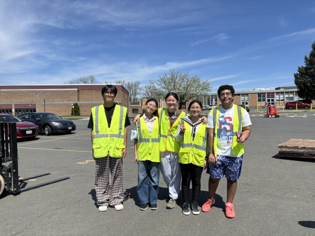 A group of people wearing safety vests pose for a photo outdoors.