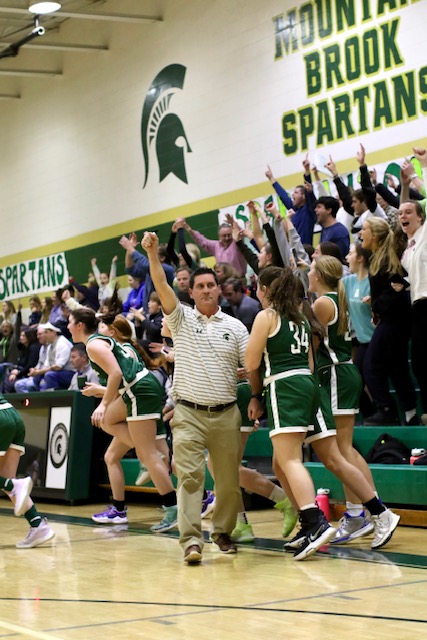 Male coach cheering on his team with the fans in the background