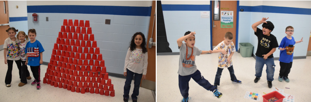 Children stand near a large tower of red cups in a school setting.