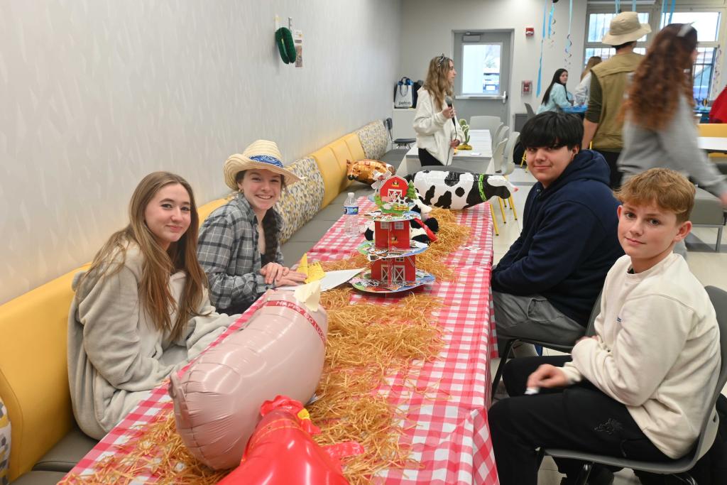 A group of young people gather around a table decorated with a farm theme.