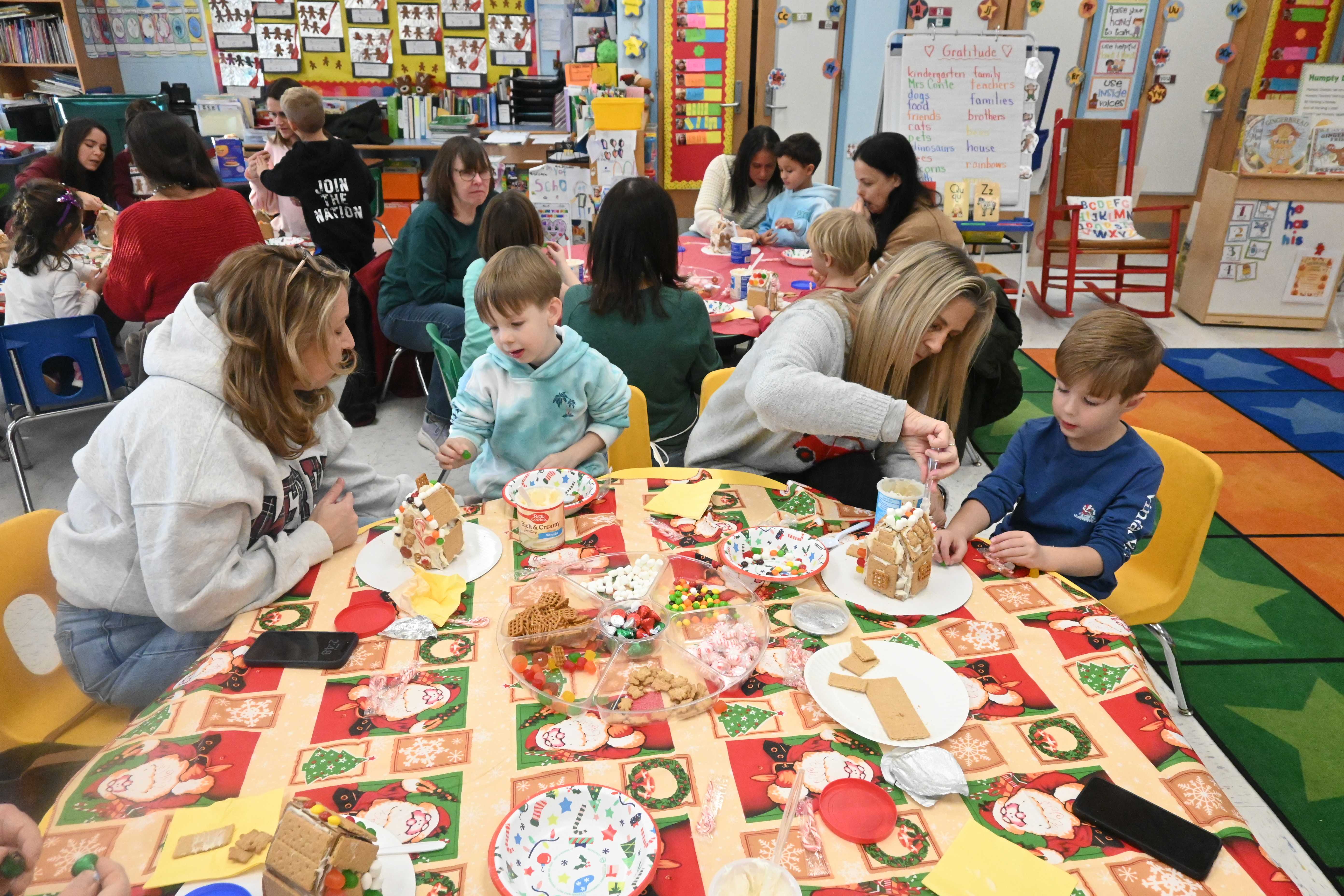 Children and adults gather around tables in a brightly lit classroom.