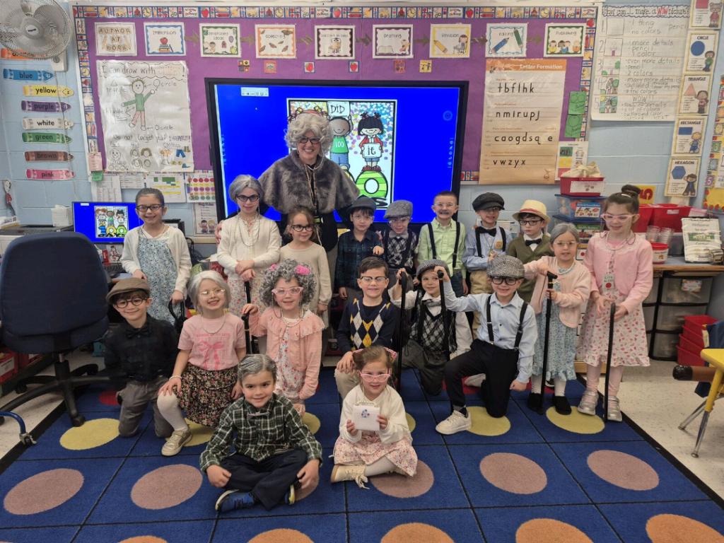 A group of children pose for a photo in a colorful classroom.