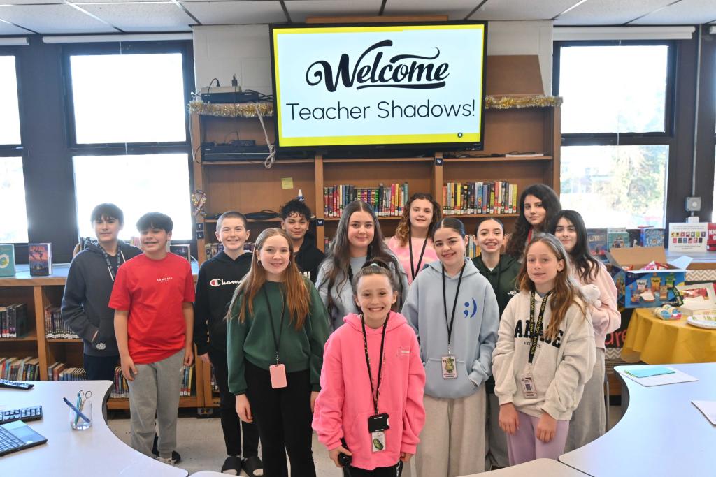 A group of students stand together in a library, smiling at the camera.