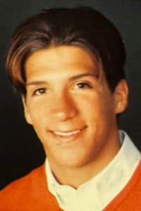 A close-up portrait of a young person, Guido Cristafori, smiling gently against a dark background in a school portrait.