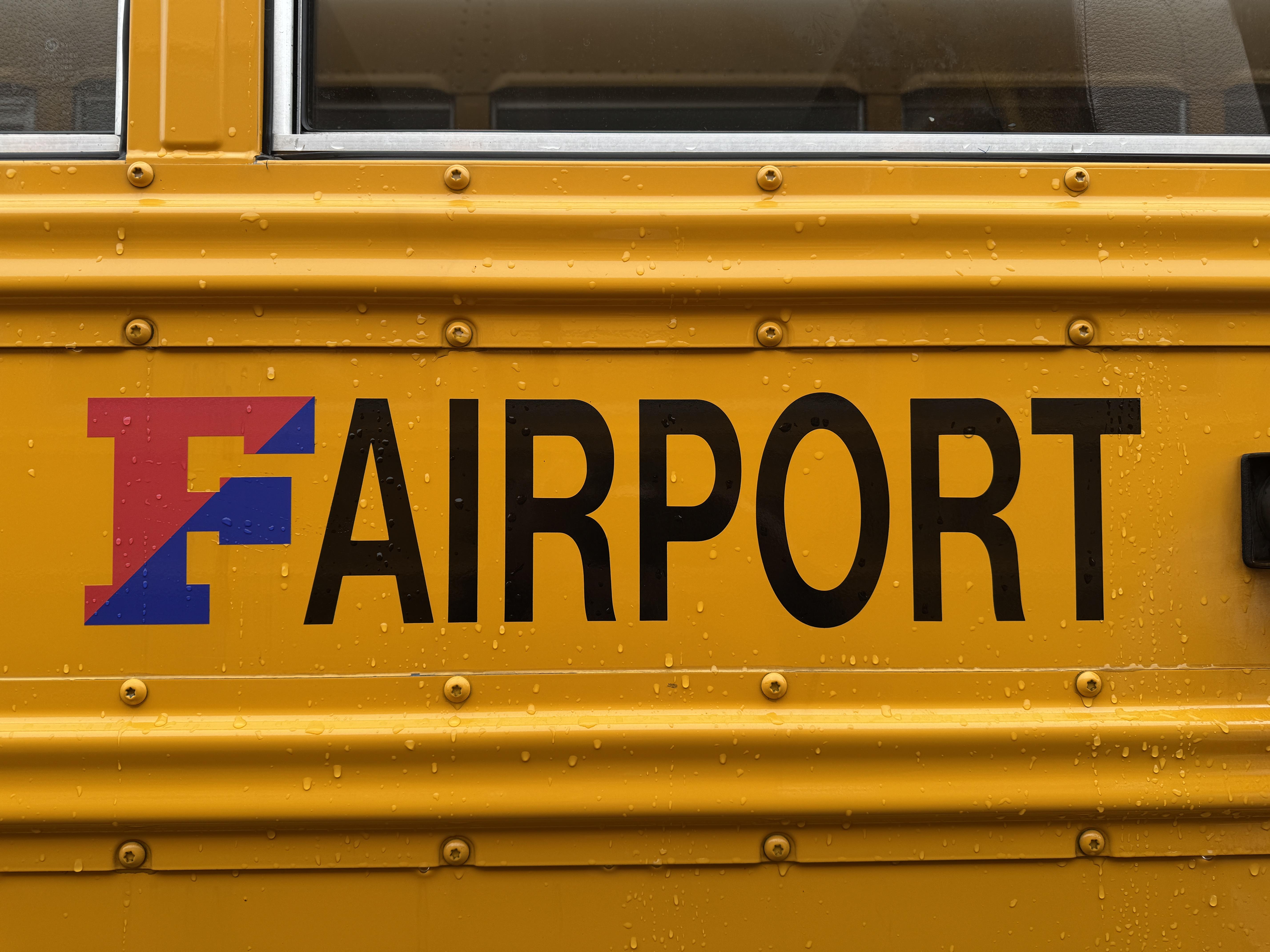 Close-up of a yellow vehicle with the word 'FAIRPORT' printed on the side.