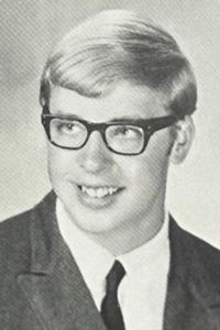 A portrait of a young person, Steve Whitman, wearing glasses, a suit jacket, and a tie for a school portrait.