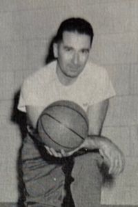 A black and white portrait of a man, coach Wes Paddock, holding a basketball.