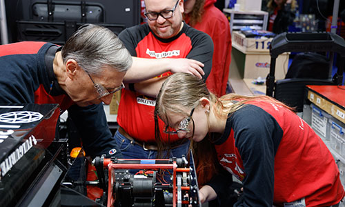 Robotics team members and mentors work on a robot.