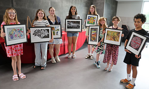 Eight students hold up their artwork.