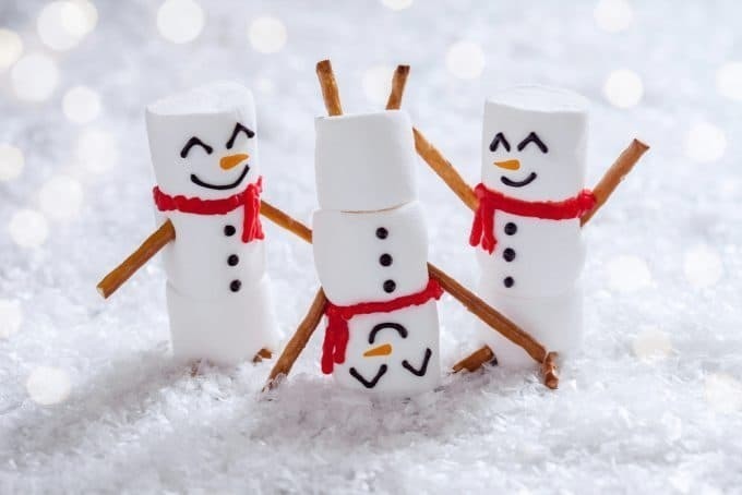 Three marshmallow snowmen playing in the snow